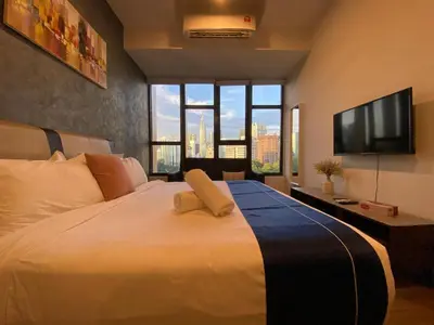 a bedroom with a large white bed with a flat screen tv at Ceylonz suites Klcc by StayLa in Kuala Lumpur