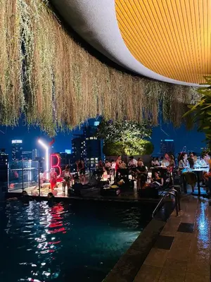 a crowd of people sitting at a pool at a restaurant at Ceylonz suites Klcc by StayLa in Kuala Lumpur