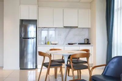 a kitchen with a table and chairs and a refrigerator at 8 min walk to Pavilion KL - Infinity Pool w TRX view in Kuala Lumpur