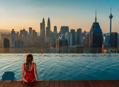 a woman sitting in a infinity pool overlooking a city at Infinity Sky Pool, Regalia KLCC in Kuala Lumpur