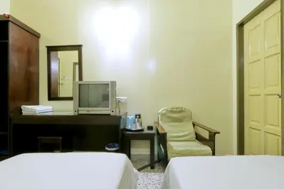 a bedroom with two beds and a desk and a television at Nan Yeang Hotel Petaling Street in Kuala Lumpur