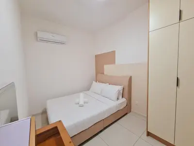 a small white bedroom with a bed and a mirror at Majestic Residence KLCC By AMG in Kuala Lumpur