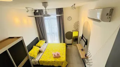 a small room with a yellow bed and a tv at Butterfly Home in Kuala Lumpur