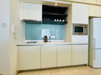 a kitchen with white cabinets and a refrigerator at The platinum KLCC by suites hospitality in Kuala Lumpur