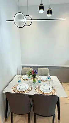 a dining room table with chairs and plates and a light fixture at Majestic Residence Suites KLCC in Kuala Lumpur