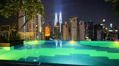 a large swimming pool with a city skyline at night at Majestic Residence Suites KLCC in Kuala Lumpur