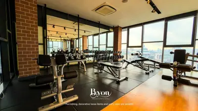 a gym with rows of exercise equipment and windows at Ceylonz Premium Suites KLCC by BYON in Kuala Lumpur