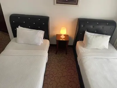 two beds in a room with a lamp on a table at Elegant Apartment at Times Square in Kuala Lumpur