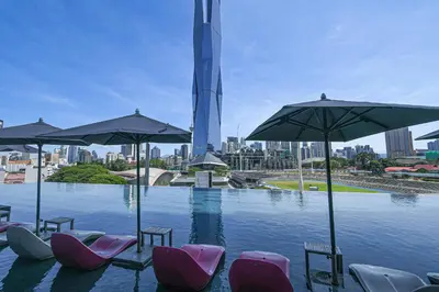 a swimming pool with chairs and umbrellas and a city at Opus Kuala Lumpur by WSD in Kuala Lumpur