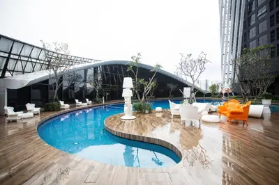a large swimming pool in a building with white furniture at Arte Mont Kiara by CozyVista Suites in Kuala Lumpur
