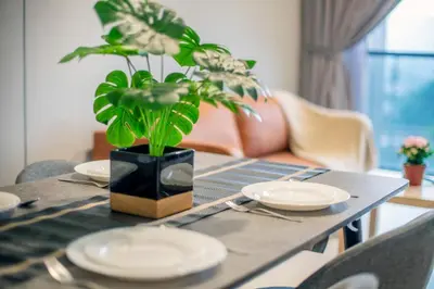a table with plates and a potted plant on it at Astoria Ampang Modern 2Bedroom Suite Free Parking in Kuala Lumpur
