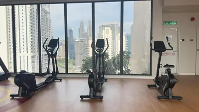 a gym with cardio equipment in front of a large window at Luxury suite for couple 267A at KLCC in Kuala Lumpur