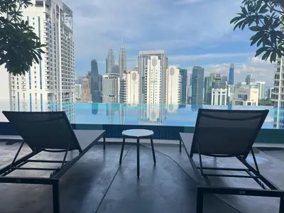 two chairs and a table on a balcony with a city skyline at Cozy suite for couples 291B at KLCC in Kuala Lumpur