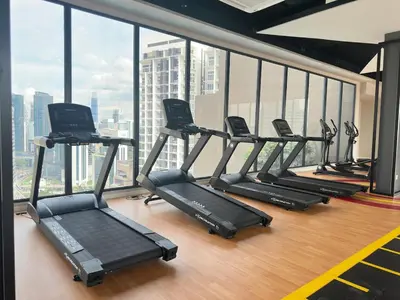 a row of treadmills in a gym with a large window at Couple suite 291A at KLCC in Kuala Lumpur
