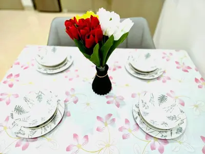 a table with plates and a vase of flowers on it at Lucentia Residence Infinity swimming pool BY Lalaport in Kuala Lumpur