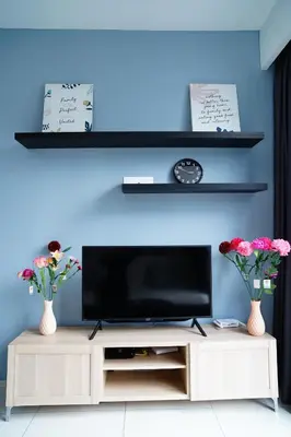 a entertainment center with a television and two vases with flowers at Bukit Bintang Robertson Residences, KLCC in Kuala Lumpur