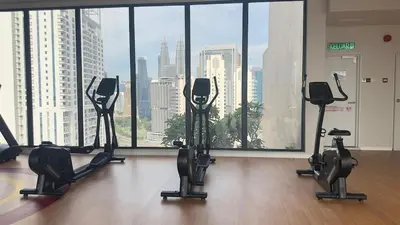 a gym with cardio equipment in front of a large window at KLCC view studio suite 272B at KLCC in Kuala Lumpur