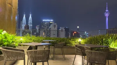 a patio with tables and chairs with a view of the city at Klcc view Luxe suite 295B at Majestic Residence in Kuala Lumpur