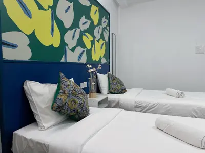 two beds with pillows in a room with a painting at Traveller Ark Hotel and Bunks in Kuala Lumpur