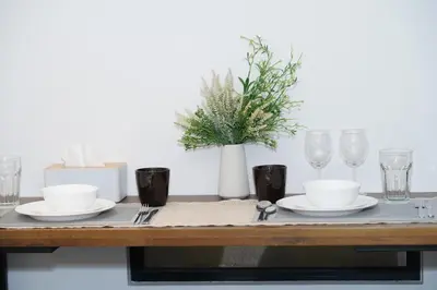 a wooden table with plates and glasses on it at Scarletz Suites By Home Stay in Kuala Lumpur