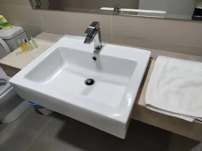 a white sink in a bathroom with a toilet at Binjai 8 Comfort Hospitality in Kuala Lumpur