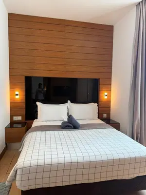 a bedroom with a large bed with a wooden headboard at Family Suites KL Sentral in Kuala Lumpur