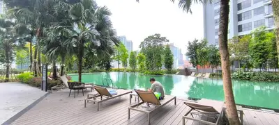 a man sitting in a chair next to a swimming pool at Service Residence Agile Delima Residence KL in Kuala Lumpur