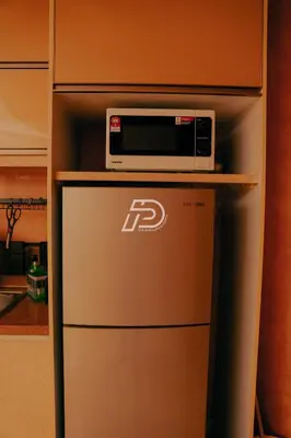 a microwave sitting on top of a refrigerator at KL Hartamas 2BR Wifi Smart TV in Kuala Lumpur