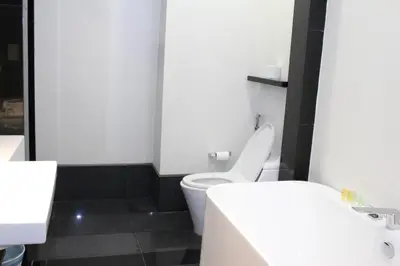 a bathroom with a white toilet and a black tile floor at The Mews KLCC Service Suites in Kuala Lumpur