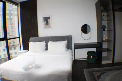 a bedroom with a bed with white sheets and a mirror at Hospitality Service Suites Scarlitz KLCC in Kuala Lumpur