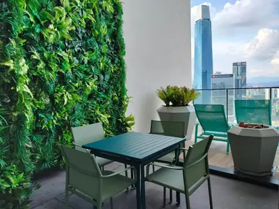 a table and chairs on a balcony with a green wall at KL City Central TRX 3 Bedrooms 2 Baths & Balcony in Kuala Lumpur