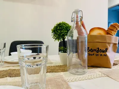 a table with a glass bottle and a basket of bread at MVA19#Family Suite 8 pax 3 Rooms Sunway Velocity Mall, MRT Maluri Cheras in Kuala Lumpur