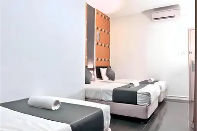a bedroom with two beds and a mirror at Hotel Pollodium Chinatown KL in Kuala Lumpur