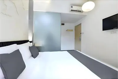 a room with a bed and a tv on a wall at Hotel Pollodium Chinatown KL in Kuala Lumpur