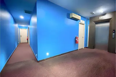a room with a blue wall and a hallway at Hotel Pollodium Chinatown KL in Kuala Lumpur