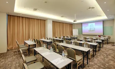 a conference room with tables and chairs and a screen at WP Hotel in Kuala Lumpur