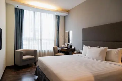 a hotel room with a bed and a chair and a window at WP Hotel in Kuala Lumpur