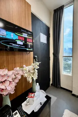 a room with a tv and flowers on a table at Swiss Hotel at City Centre in Kuala Lumpur