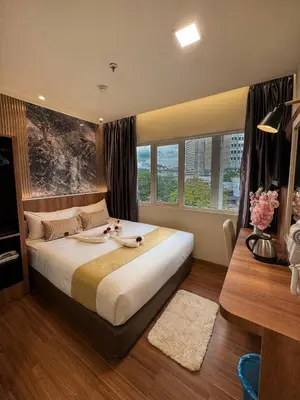 a bedroom with a large bed and a desk at Swiss Hotel at City Centre in Kuala Lumpur