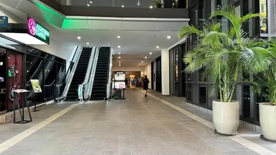 a hallway in a shopping mall with palm trees at Couple Private studio B22 11 Trion KL in Kuala Lumpur