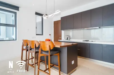 a kitchen with brown chairs and a wooden counter top at Gleneagles Hospital - 3BR with Pool & Near KLCC in Kuala Lumpur