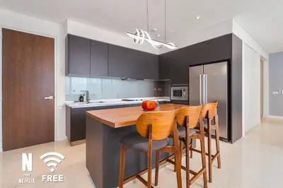 a kitchen with black cabinets and a wooden table and chairs at Gleneagles Hospital - 3BR with Pool & Near KLCC in Kuala Lumpur