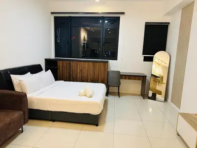 a bedroom with a bed and a couch and a window at Chamber Haven KL in Kuala Lumpur