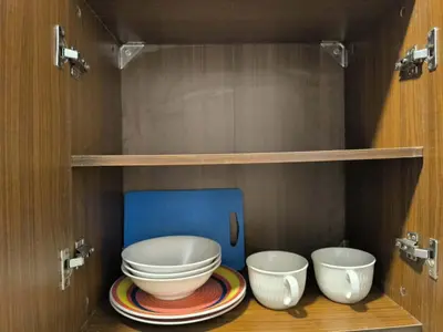 a cabinet with three bowls and plates on a shelf at Neu Suites in Kuala Lumpur