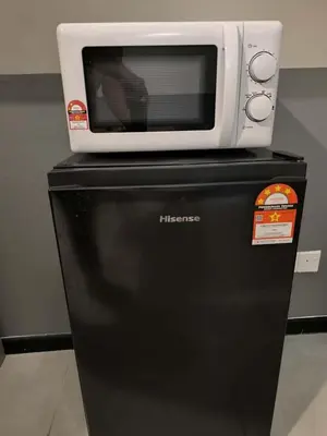a microwave sitting on top of a black refrigerator at Neu Suites in Kuala Lumpur