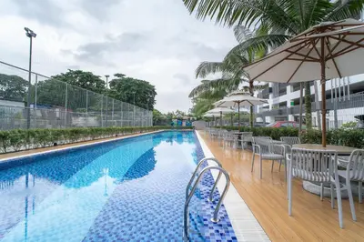 a swimming pool with tables and chairs and an umbrella at 6 pax Modern 3BR Stay in Sentul near KL City in Kuala Lumpur