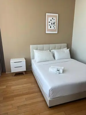 a bedroom with a white bed and a night stand at Skysuites Twin Tower Prime Location in Kuala Lumpur