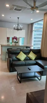 a living room with a black leather couch with yellow pillows at SOHO Suites KLCC by noon in Kuala Lumpur