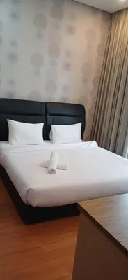 a bed with a black head board and white pillows at SOHO Suites KLCC by noon in Kuala Lumpur