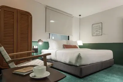 a bedroom with a bed and a table and a chair at Swing & Pillows - Kentomen Hotel, Bamboo Hills in Kuala Lumpur